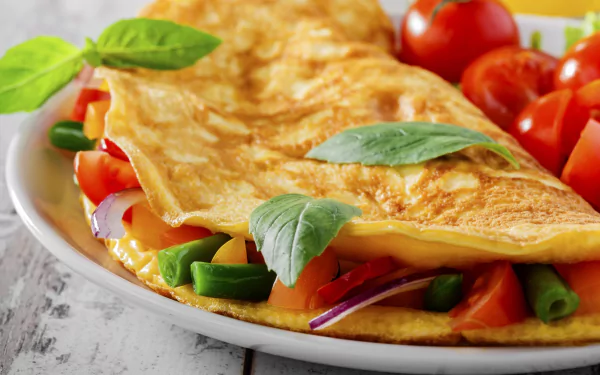 HD desktop wallpaper featuring a close-up of a golden omelette garnished with fresh basil leaves, served with sliced tomatoes and vegetables on a white plate.