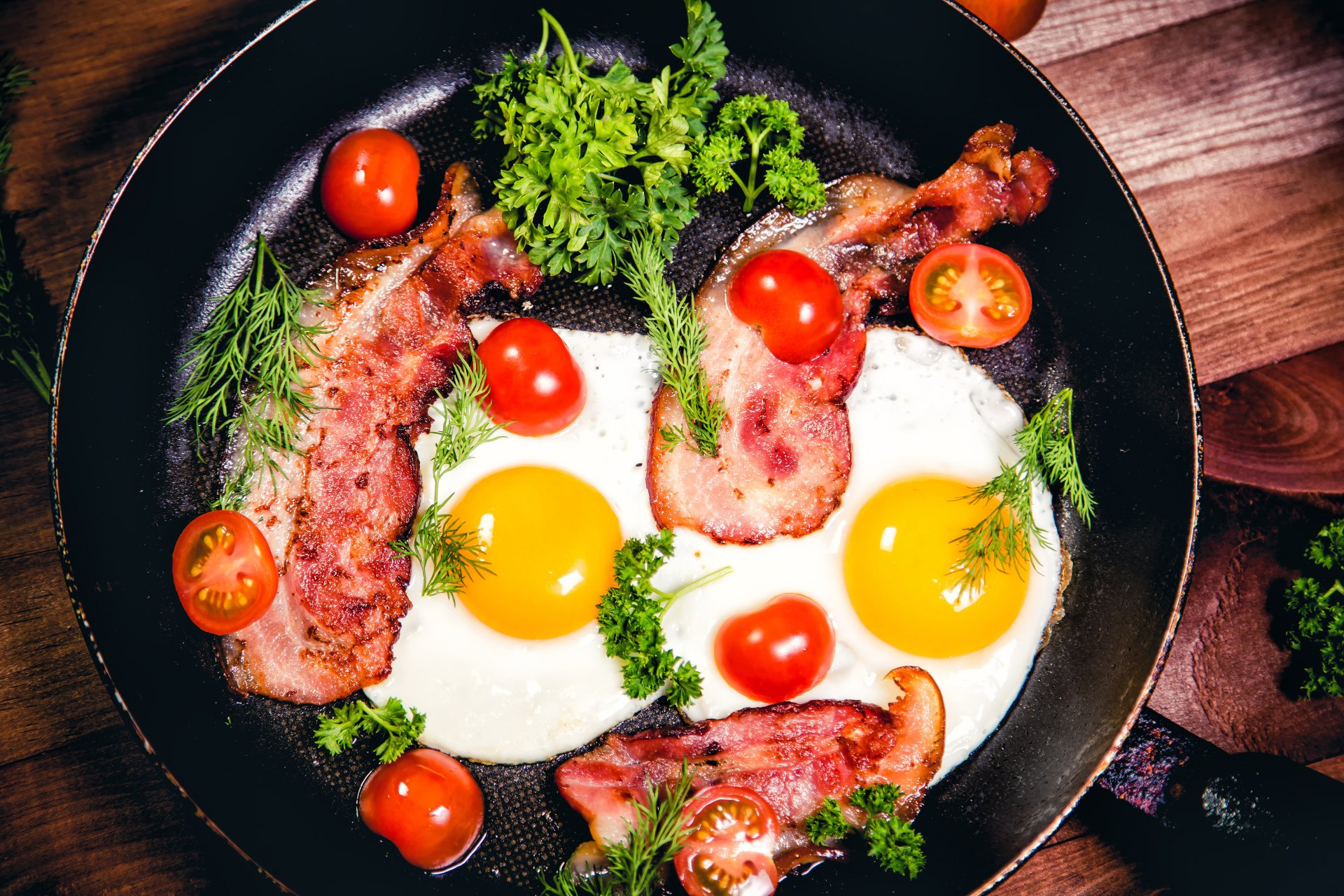 5K Ultra HD PC desktop wallpaper: still-life breakfast skillet with sunny-side-up eggs, crispy bacon strips, cherry tomatoes and fresh herbs.