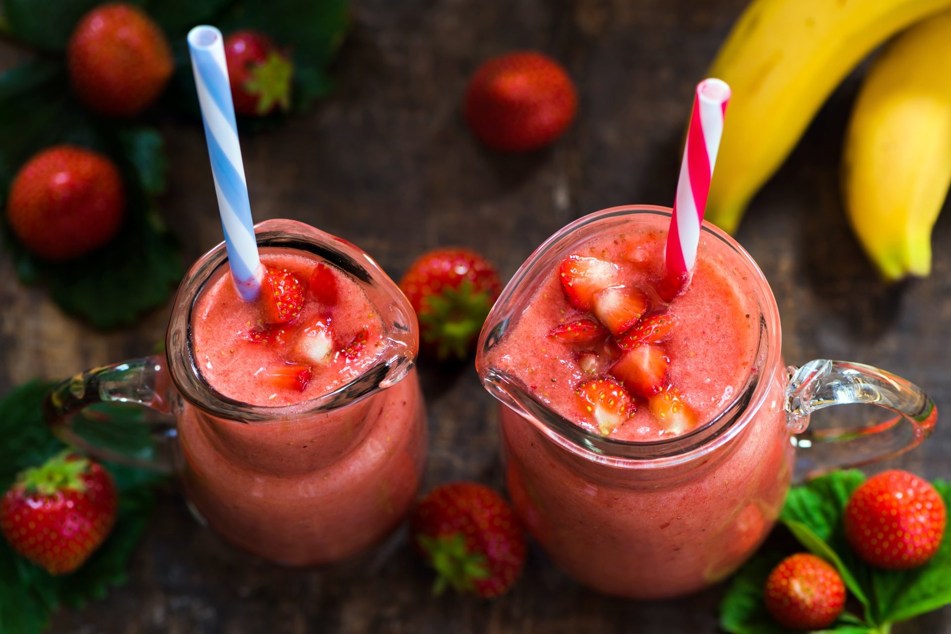 8K Ultra HD PC desktop wallpaper — still-life of two strawberry smoothies in glass jars with diced fruit, surrounded by strawberries and bananas.