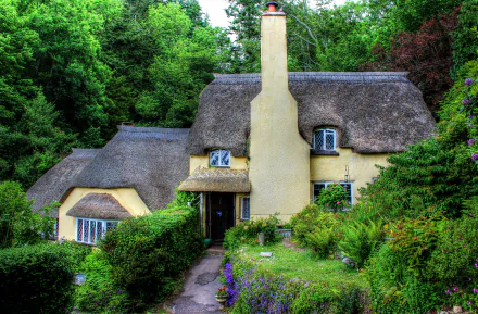 A charming thatched roof cottage surrounded by lush greenery and blooming flowers in spring, set in the English countryside. 4K Ultra HD wallpaper.
