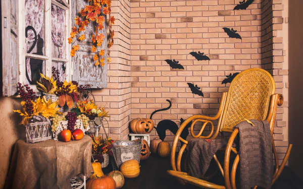 4K Ultra HD Halloween holiday scene with pumpkins, autumn leaves, black bats on brick wall, and cozy rocking chair in a warm, festive indoor corner.