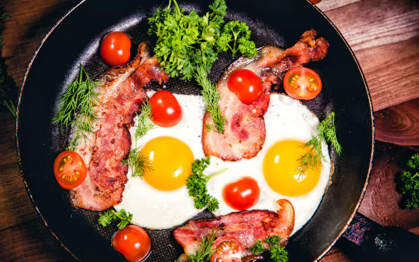 5K Ultra HD PC desktop wallpaper: still-life breakfast skillet with sunny-side-up eggs, crispy bacon strips, cherry tomatoes and fresh herbs.