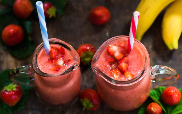 8K Ultra HD PC desktop wallpaper — still-life of two strawberry smoothies in glass jars with diced fruit, surrounded by strawberries and bananas.
