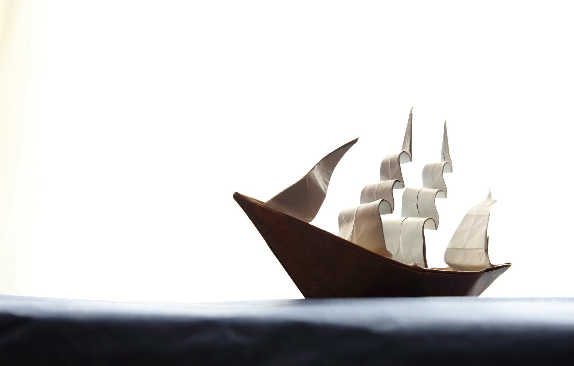 HD desktop wallpaper featuring a man-made origami paper boat with detailed sails against a bright, minimalist background.