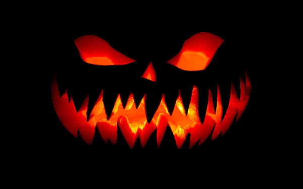 A hauntingly carved jack-o'-lantern glows menacingly against a dark background, capturing the spirit of Halloween in this vivid HD desktop wallpaper.