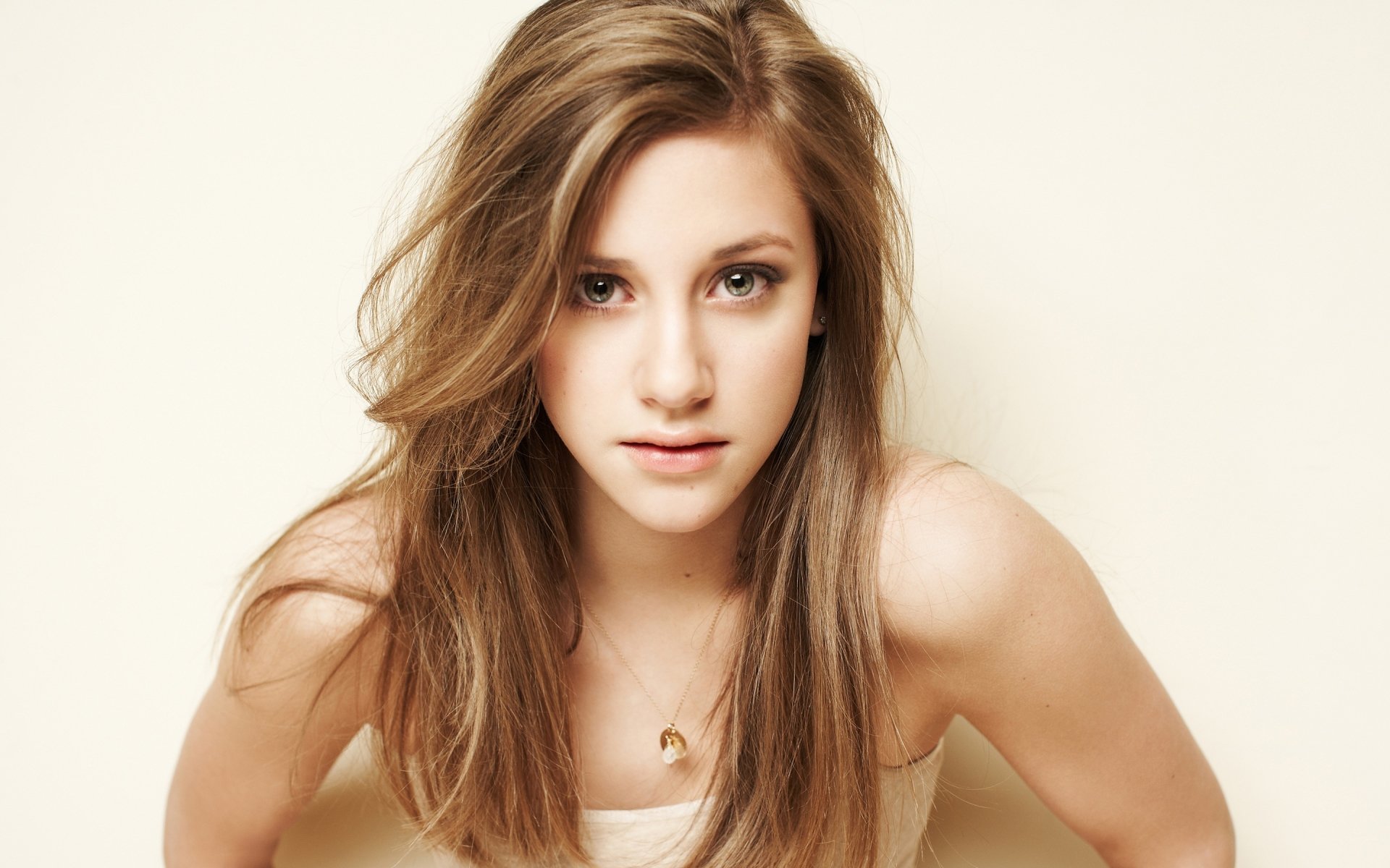 Close-up HD desktop wallpaper of American actress Lili Reinhart with blonde hair, looking directly at the camera against a neutral background.