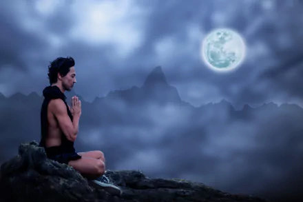 A person practices yoga meditation on a mountain at night under a glowing full moon, captured in stunning 4K Ultra HD photography.
