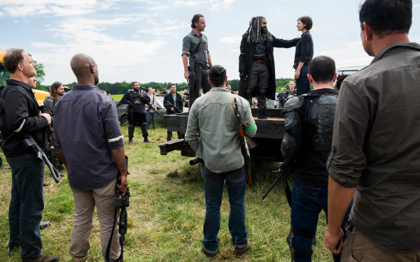 4K PC desktop wallpaper: a crowd of survivors from The Walking Dead gathers in a grassy field around a raised platform as leaders address the group.