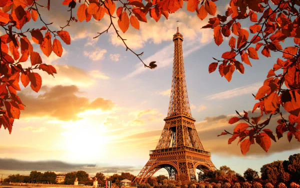 4K Ultra HD view of the Eiffel Tower in Paris framed by vibrant fall leaves under a dramatic sky, showcasing the iconic man-made monument in autumn.
