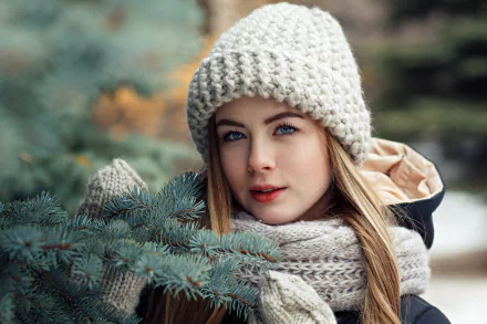 Close-up 4K Ultra HD portrait of a blonde woman with blue eyes wearing a knitted hat and scarf, showcasing soft depth of field and natural makeup with lipstick.