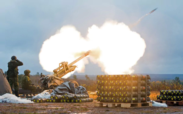 HD PC desktop wallpaper showing a soldier operating military artillery during a live firing exercise in an open field.