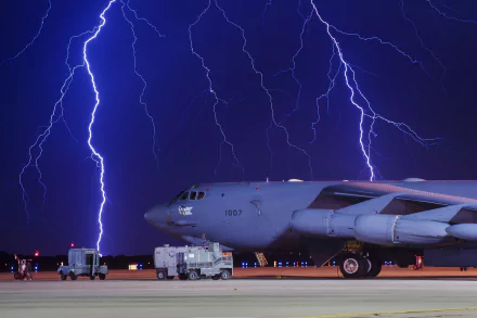 Boeing B-52 Stratofortress warplane on the tarmac at night with dramatic lightning bolts in the background.