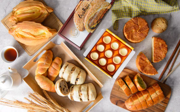 HD PC desktop wallpaper still life of viennoiserie and food: croissants, filled pastries, rolls, teapot and wheat stalks arranged on a marble background.