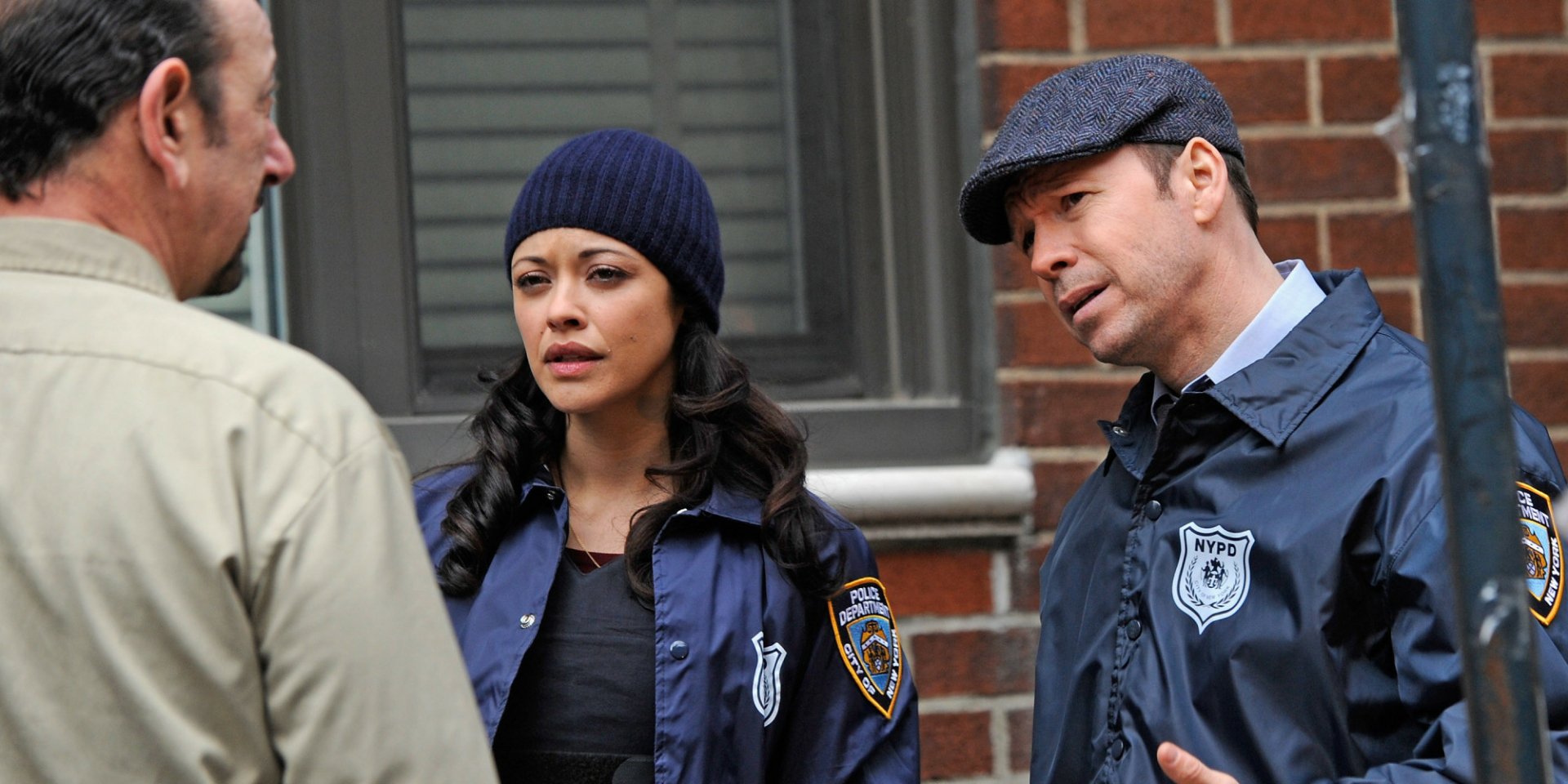 HD wallpaper of two Blue Bloods TV series characters dressed in NYPD uniforms, having a conversation on the street.
