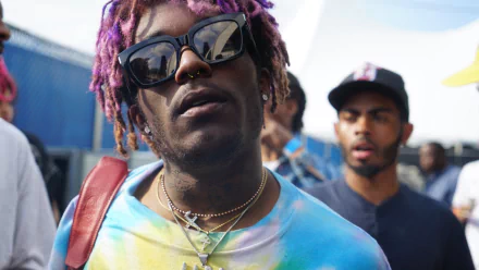 HD desktop wallpaper featuring a person with purple hair and sunglasses, tagged as Lil Uzi Vert, with a blurry background.
