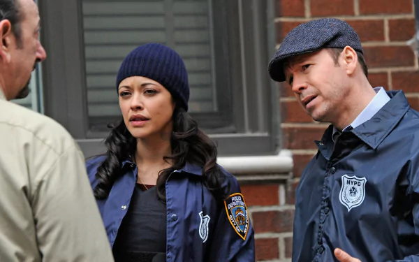 HD wallpaper of two Blue Bloods TV series characters dressed in NYPD uniforms, having a conversation on the street.