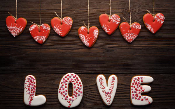 HD desktop wallpaper featuring heart-shaped cookies hanging on strings and the word LOVE spelled out with decorated cookies, expressing a Valentine's Day theme with a romantic and artistic touch.