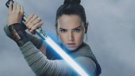 Rey from Star Wars: The Last Jedi, portrayed by Daisy Ridley, in a dynamic pose wielding a blue lightsaber, featured in an HD PC desktop wallpaper.