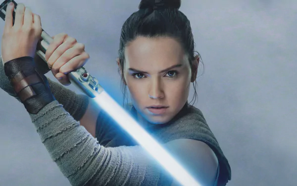 Rey from Star Wars: The Last Jedi, portrayed by Daisy Ridley, in a dynamic pose wielding a blue lightsaber, featured in an HD PC desktop wallpaper.