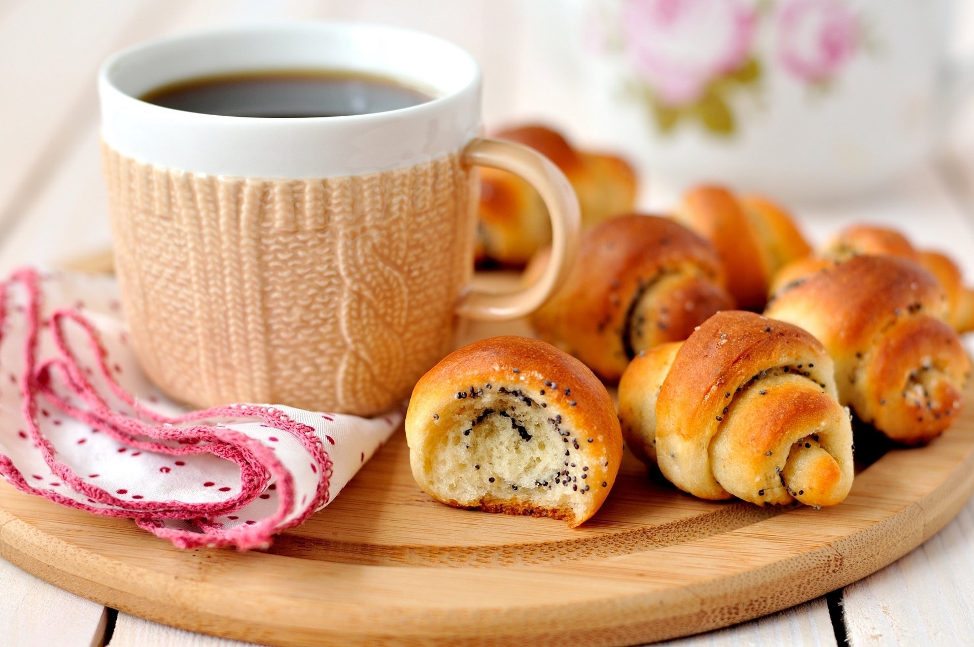 HD desktop wallpaper featuring a cozy cup of coffee in a knitted sleeve alongside fresh viennoiserie on a wooden board, highlighting food and drink.