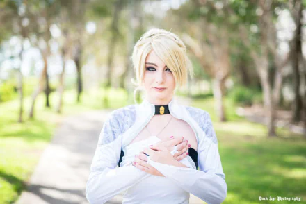 HD PC desktop wallpaper of a woman in Final Fantasy cosplay: blond-haired cosplayer in white costume and choker standing on a sunlit tree-lined path.