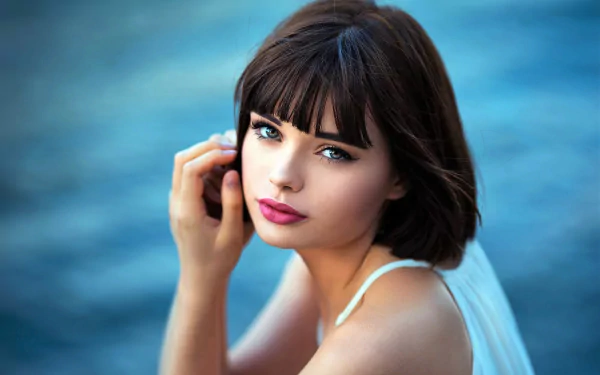 Close-up portrait of brunette model Marie Grippon with lipstick, looking over her shoulder against a blurred blue background, captured in HD for a desktop wallpaper.