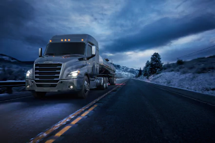 A Freightliner Cascadia truck drives on a snowy highway under a dramatic cloudy sky, captured in 4K Ultra HD for a PC desktop wallpaper.