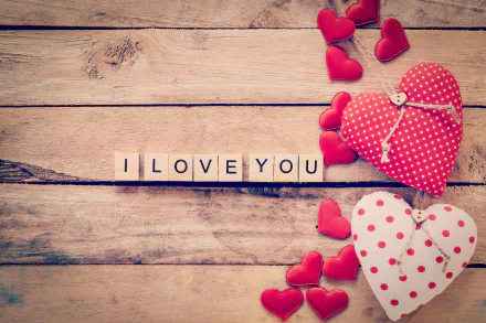 Romantic 4K Ultra HD wallpaper featuring heart-shaped fabric decorations and wooden blocks spelling I LOVE YOU on a rustic wooden background.