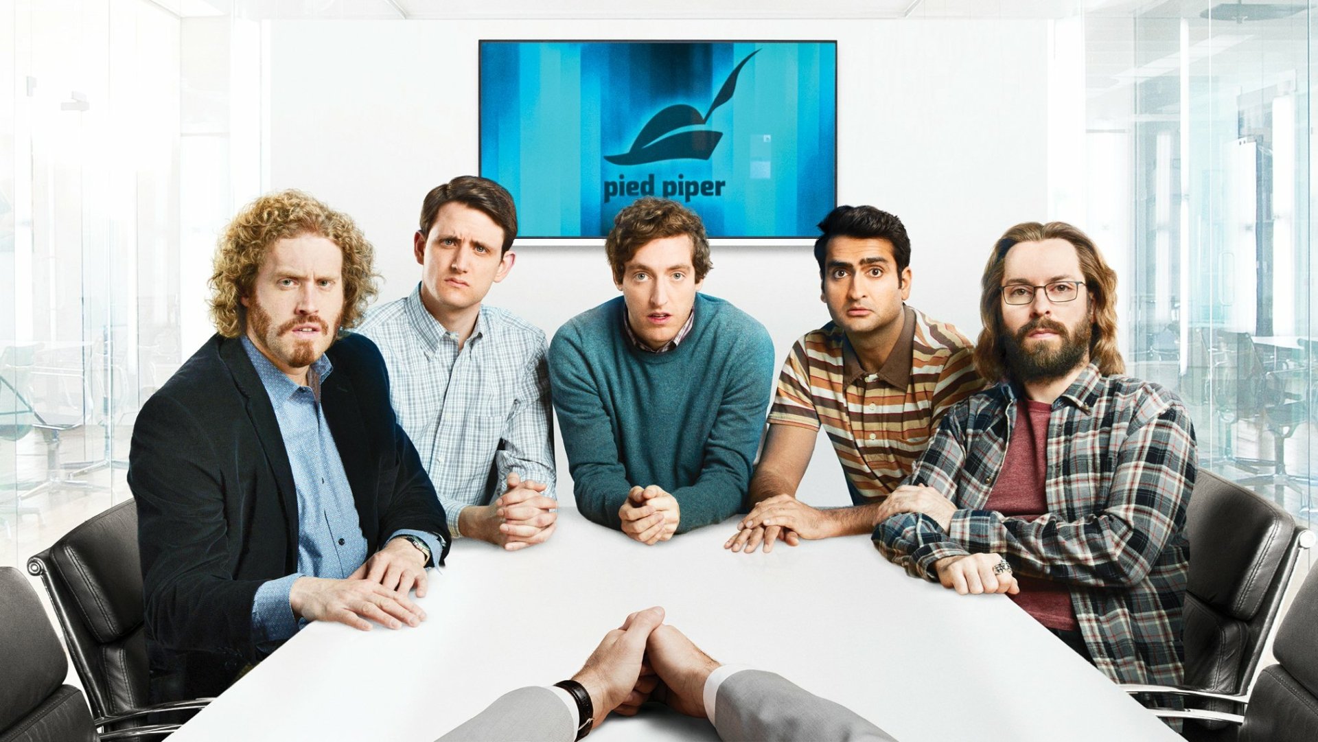 HD desktop wallpaper featuring the main cast of the TV show Silicon Valley seated around a conference table with the Pied Piper logo on a screen behind them.