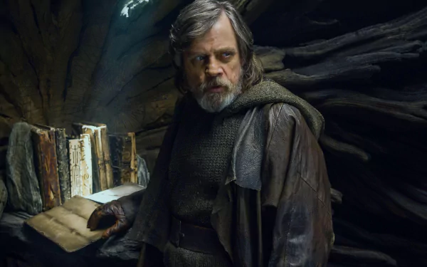 Luke Skywalker from Star Wars: The Last Jedi stands in a dimly lit cave, holding a book, captured in this 4K Ultra HD PC desktop wallpaper.