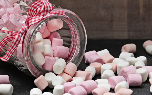 HD desktop wallpaper featuring a jar of pink and white marshmallow sweets spilling onto a dark surface, creating a cozy and colorful food-themed background.
