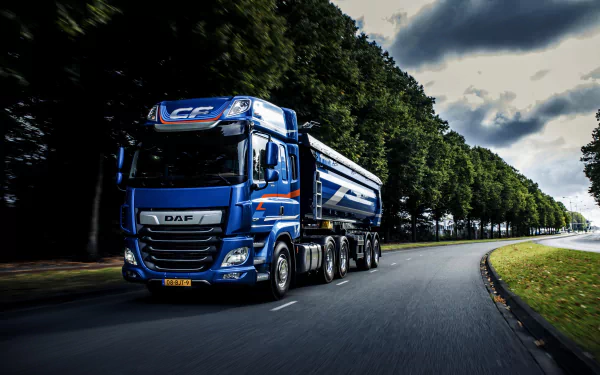 A blue DAF vehicle drives along a tree-lined road under a cloudy sky, captured in vibrant 4K Ultra HD as a PC desktop wallpaper and background.