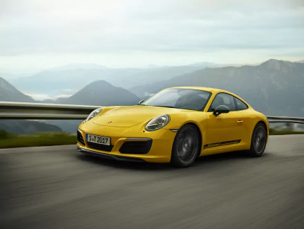 Yellow Porsche 911 Carrera T sports car driving on a mountainous road, captured in 4K Ultra HD for a dynamic PC desktop wallpaper.