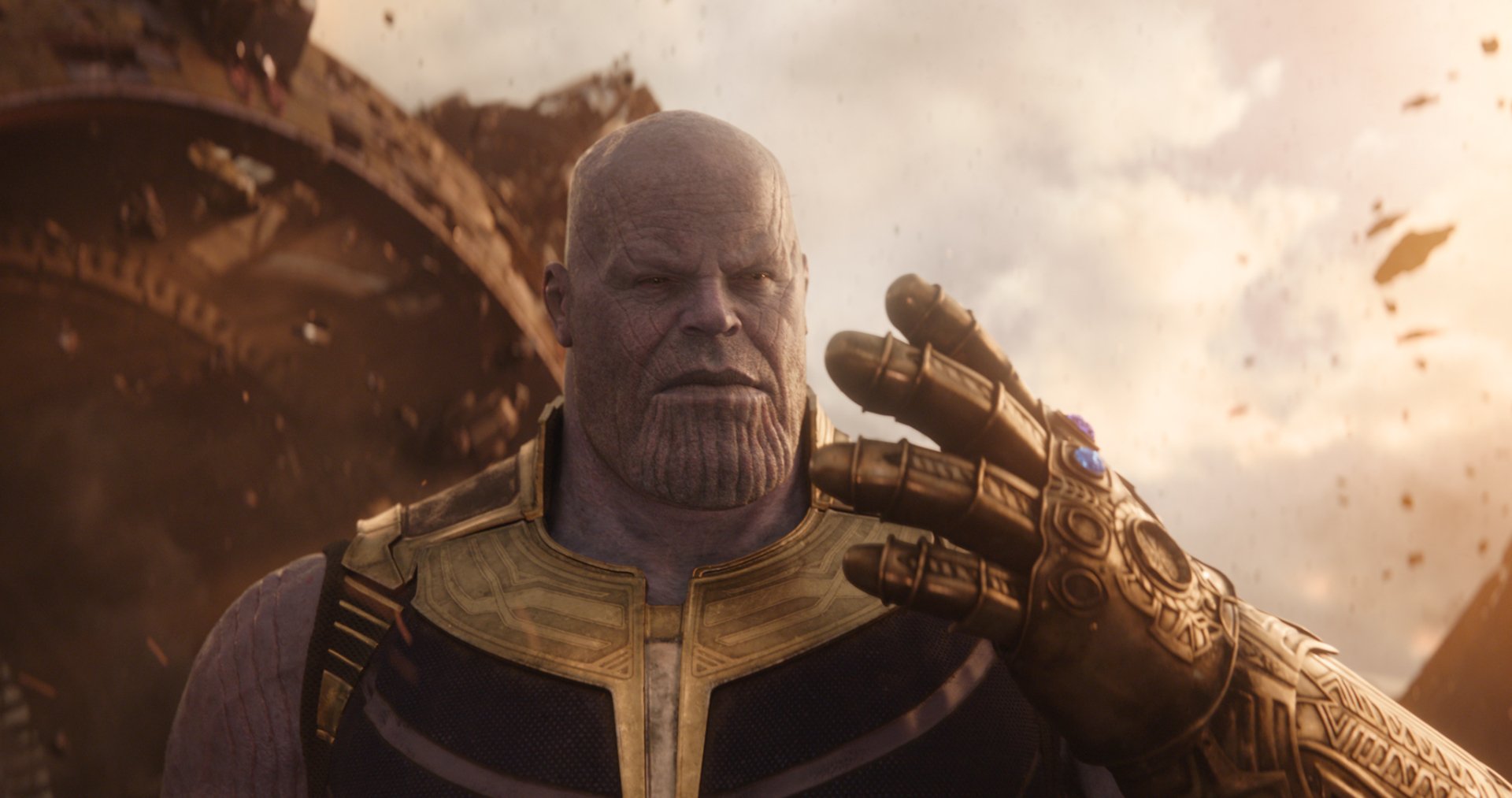 HD desktop wallpaper of Thanos, portrayed by Josh Brolin in the movie Avengers: Infinity War. Thanos is shown wearing his armor and the Infinity Gauntlet, with a menacing expression amidst a chaotic background.
