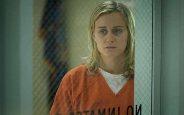 HD PC desktop wallpaper/background from the TV show Orange Is the New Black: woman in an orange prison uniform behind wired glass, looking solemn.