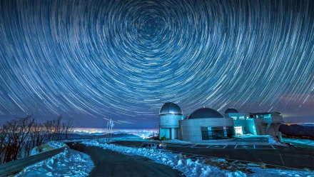 HD desktop wallpaper showing an observatory under a vivid star trail sky at night, capturing stunning long-exposure night sky photography.