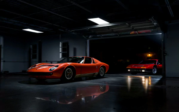 Orange Lamborghini Miura in a dim garage with glossy floor reflections, a second Miura in the background — HD PC desktop wallpaper of a classic car/vehicle.