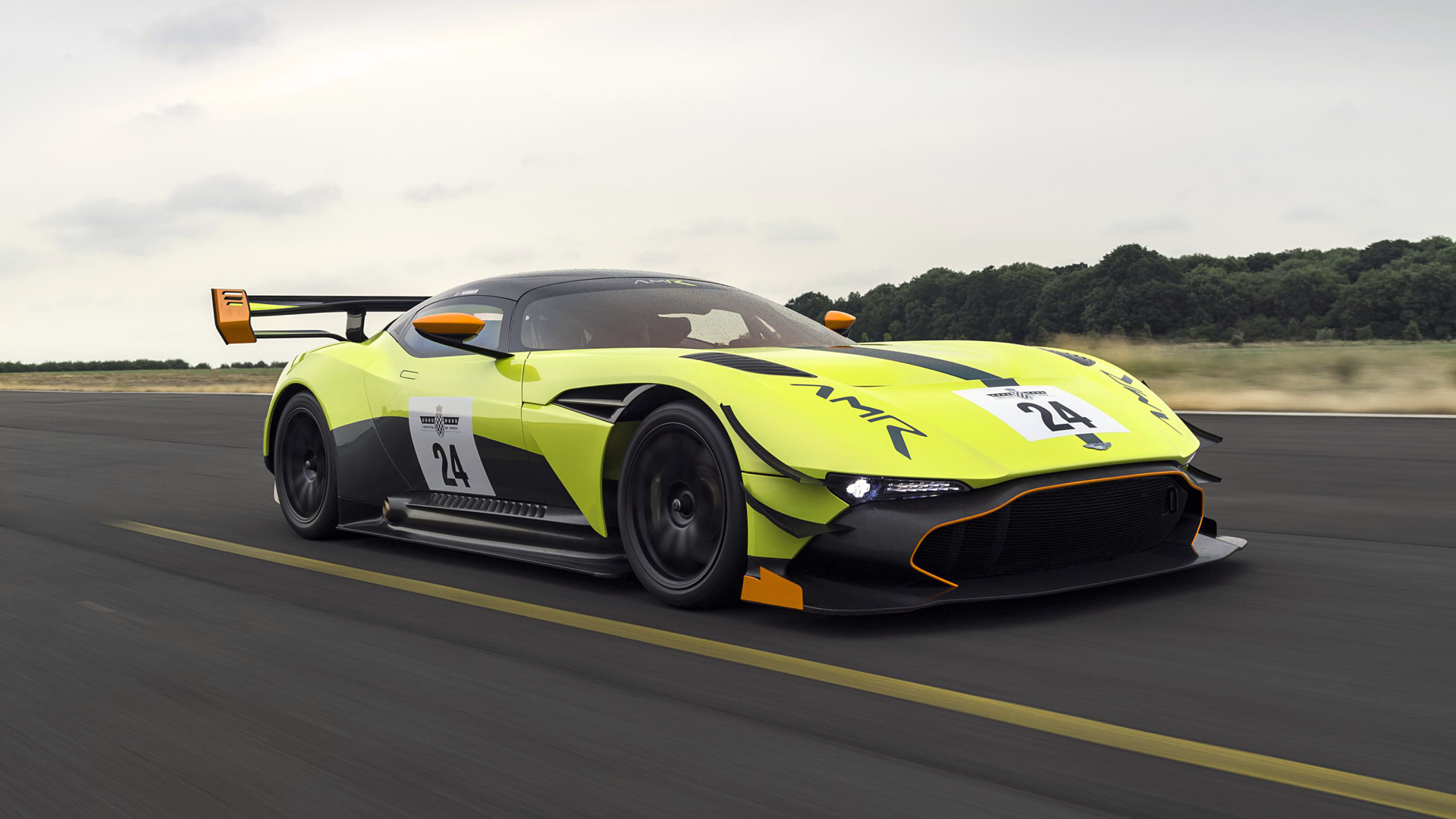 Aston Martin Vulcan AMR Pro supercar in neon yellow-green with race livery and rear wing, speeding on track — 2K Quad HD PC desktop wallpaper background.