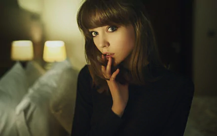 HD desktop wallpaper featuring Olya Pushkina, a brunette model with green eyes, posing thoughtfully in a softly lit room.