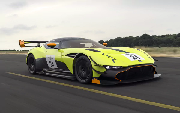 Aston Martin Vulcan AMR Pro supercar in neon yellow-green with race livery and rear wing, speeding on track — 2K Quad HD PC desktop wallpaper background.