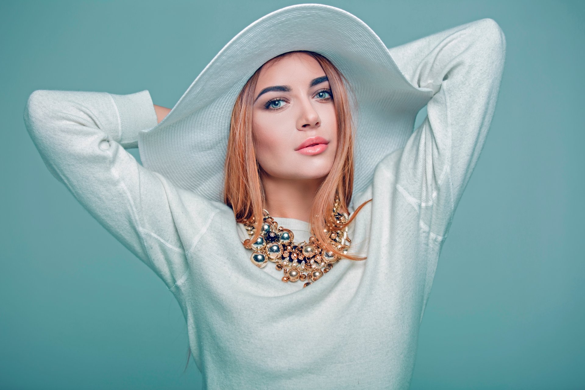 5K Ultra HD PC desktop wallpaper of a model woman wearing a wide-brim hat, bold lipstick and a layered statement necklace against a soft teal background.