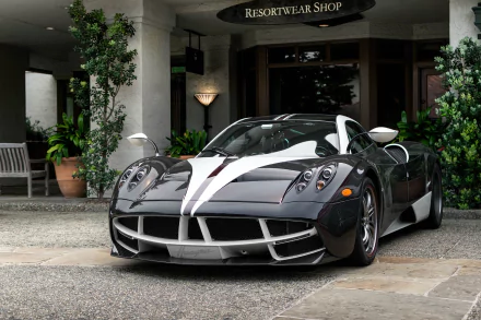 Black Pagani Huayra supercar with white racing stripes parked in front of a building, showcased as an HD PC desktop wallpaper and background.