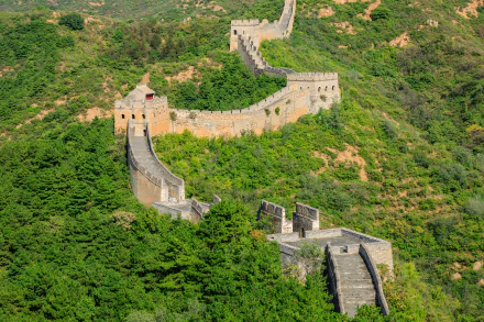 A 4K Ultra HD image of the man-made Great Wall of China winding through lush green hills, showcasing its historic architecture and natural surroundings.