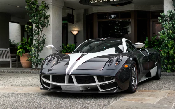 Black Pagani Huayra supercar with white racing stripes parked in front of a building, showcased as an HD PC desktop wallpaper and background.