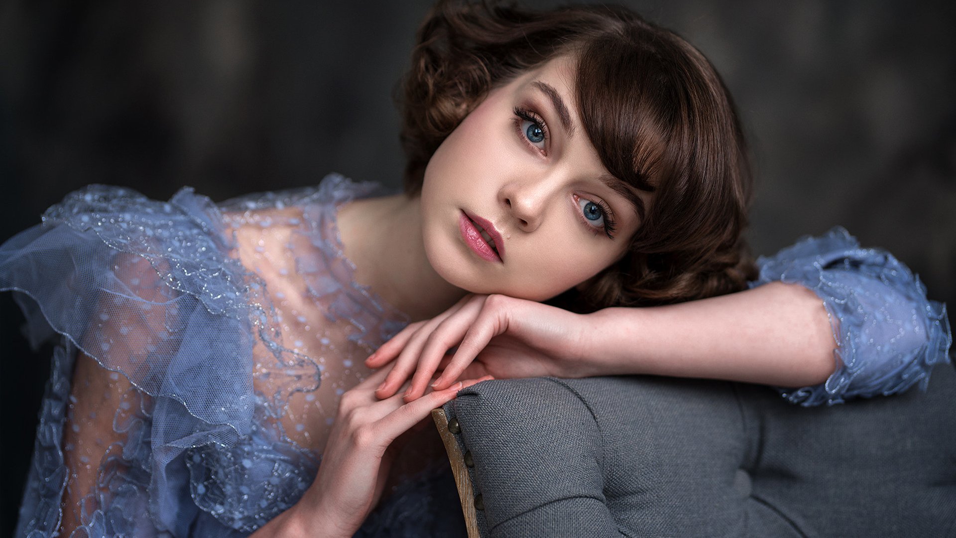 HD desktop wallpaper featuring model Olya Pushkina with short brunette hair, striking blue eyes, and subtle lipstick, wearing a delicate lace dress.