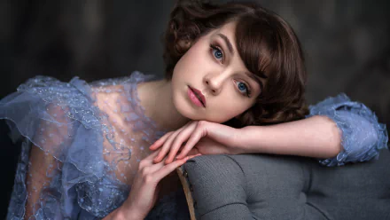 HD desktop wallpaper featuring model Olya Pushkina with short brunette hair, striking blue eyes, and subtle lipstick, wearing a delicate lace dress.