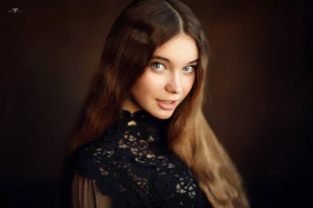 HD desktop wallpaper of a brunette woman with long hair and striking blue eyes, posing confidently as a model against a dark, blurred background.