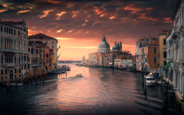 A stunning HD wallpaper of Venice, Italy, featuring the Grand Canal at sunset with a view of a domed building in the background and historic city buildings lining the canal under a dramatic sky.