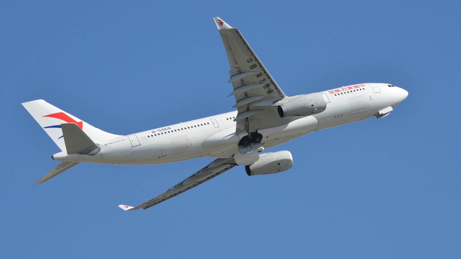 A white Airbus A330 passenger plane flying against a clear blue sky, captured in high-definition for desktop wallpaper and background use.