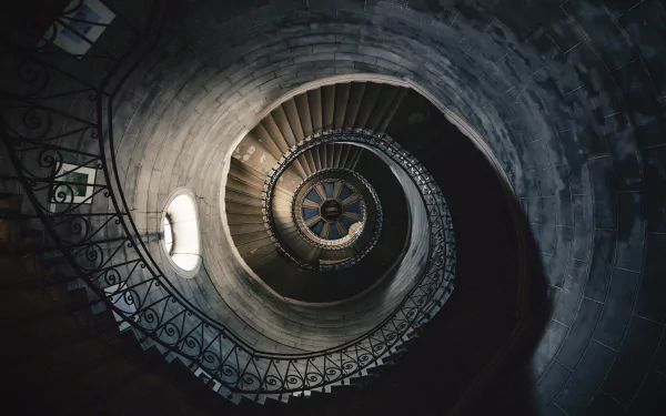 HD desktop wallpaper featuring a stunning man-made spiral staircase winding upwards, captured with rich detail and shadow play, creating a mesmerizing visual effect.